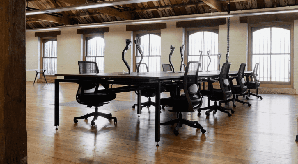 A single row dark desk and chairs on a wooden floor.