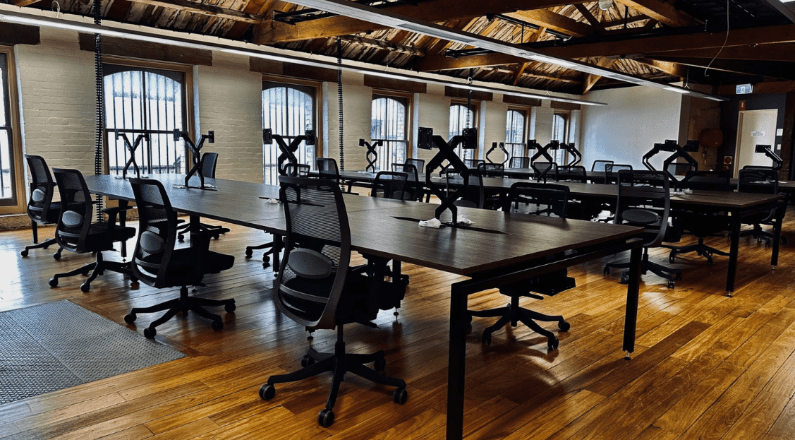 A beautiful office fitout, dark desks and black chairs on wooden floor.